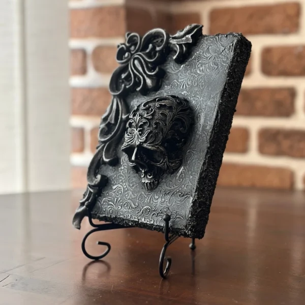 Vestigium · Obra de arte en relieve con calavera barroca y volutas envejecidas sobre fondo negro mate